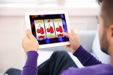 Online casino oyunu evde oynamak için tablet kullanan adam