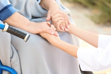Elele kadın kıdemli, açık havada, closeup tekerlekli ev bakım genç hemşire