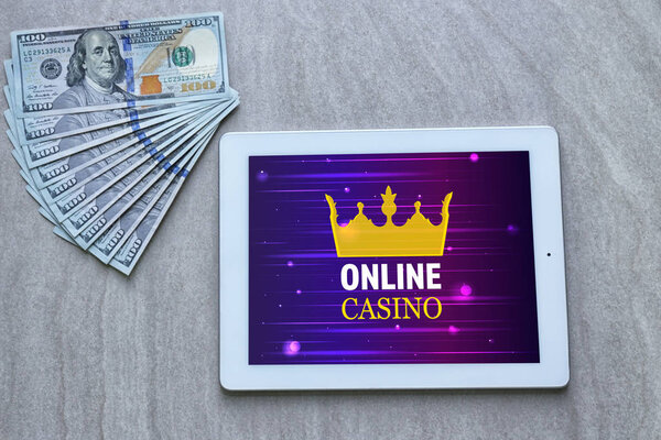 Tablet with online casino app and money on table