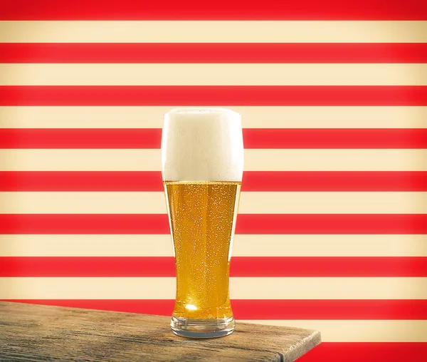 Glass of beer on wooden table against patterned background