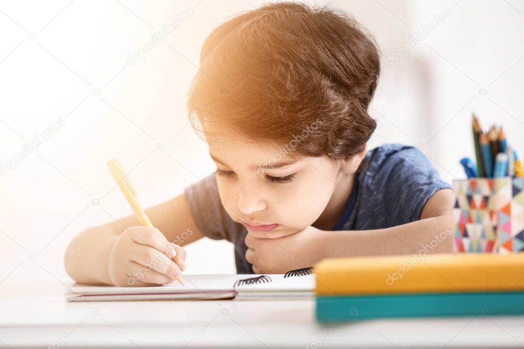 Little boy doing homework at table in room