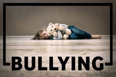 Word bullying ve üzgün kız oyuncakla kapalı yerde yatarken