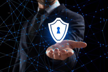 Sanal kalkan koyu arka planda tutan bir iş adamı. Siber güvenlik ve saldırı kavramı