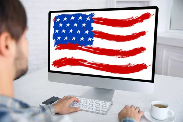 在桌上屏幕上使用美国国旗的电脑的年轻人 — 图库照片