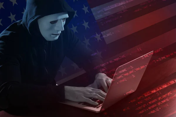 Double exposure of hacker in mask working with laptop and USA flag. Threat of cyber attack against goverment