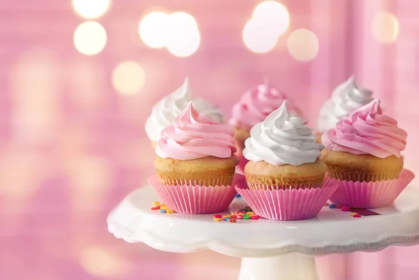 Fique com cupcakes saborosos e luzes embaçadas no fundo de cor — Fotografia de Stock