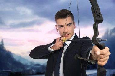 Genç işadamı pratik okçuluk ve manzara arka plan üzerinde