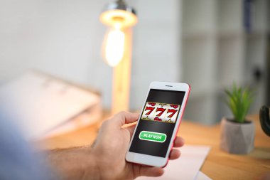 Online casino oyunu evde oynamak için akıllı telefon kullanan adam