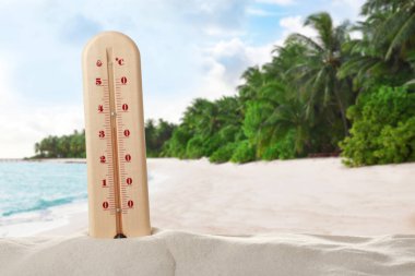 Thermometer showing high temperature on tropical beach. Hot summer weather clipart