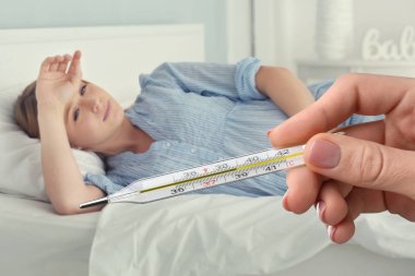 Doktor holding termometre ile yüksek sıcaklık ve hasta hamile kadın evde yatakta yatarken