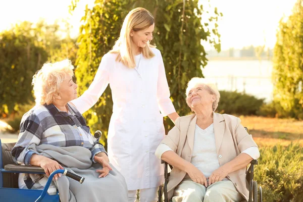 Verpleegkundige uit verzorgingsinstelling wandelen met senior mensen buiten — Stockfoto