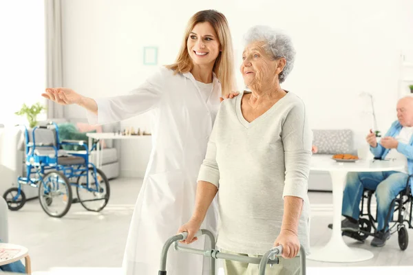 Mujer mayor con caminantes y enfermera en el hogar de cuidado — Foto de Stock