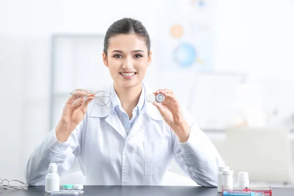 Médico femenino sosteniendo estuche de lentes de contacto y gafas en interiores — Foto de Stock