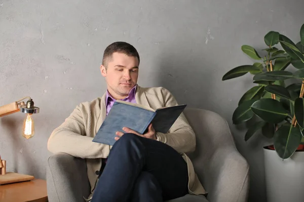 Volwassen man in casual kleding lezen boek thuis — Stockfoto