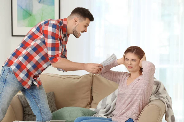 Hombre enojado regañando a su esposa por gastar en exceso en casa —  Fotos de Stock