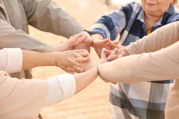 Pessoas idosas de casa de cuidados colocando as mãos juntas como símbolo de unidade ao ar livre — Fotografia de Stock