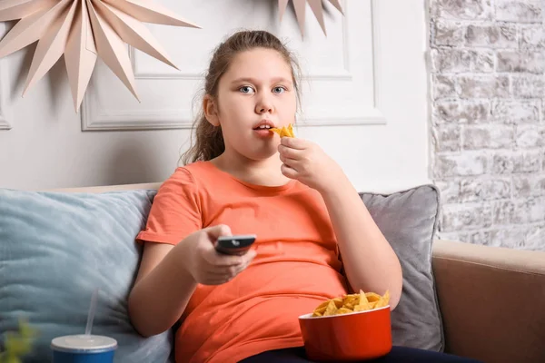 超重的女孩看电视与零食室内 — 图库照片