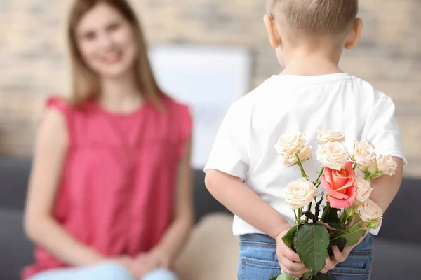 Ładny mały chłopiec trzyma kwiaty dla matki za jego plecami, zbliżenie — Zdjęcie stockowe