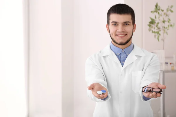 Doctor sosteniendo contenedor de plástico con lentes de contacto y gafas en la clínica — Foto de Stock