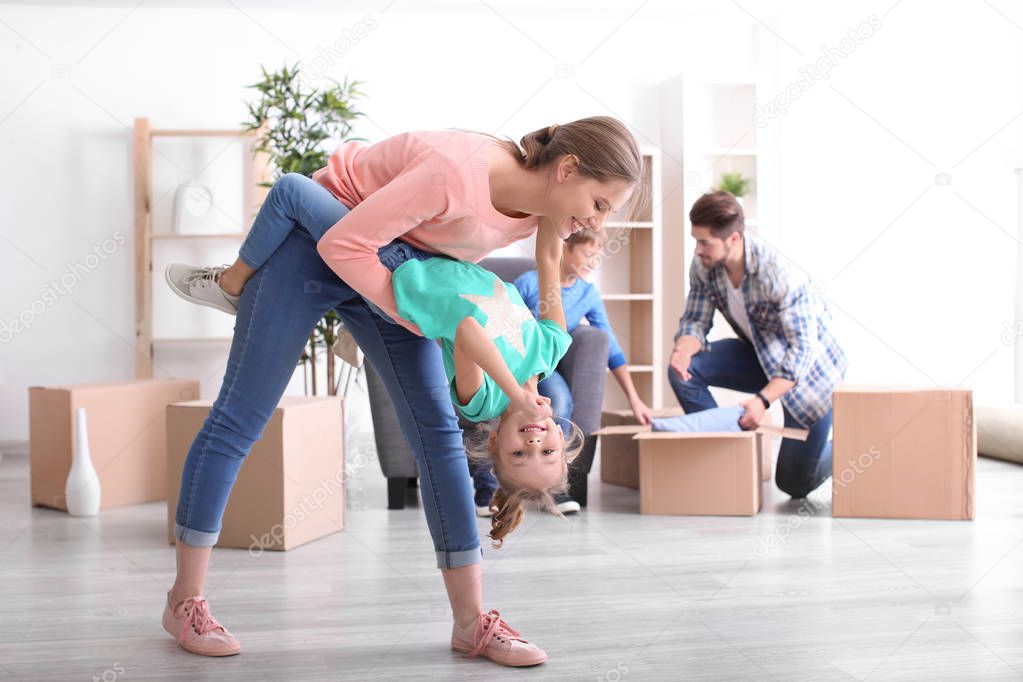 Young woman playing with her daughter. Happy family on moving day