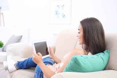 Tablet bilgisayar evde kanepede kullanan genç kadın