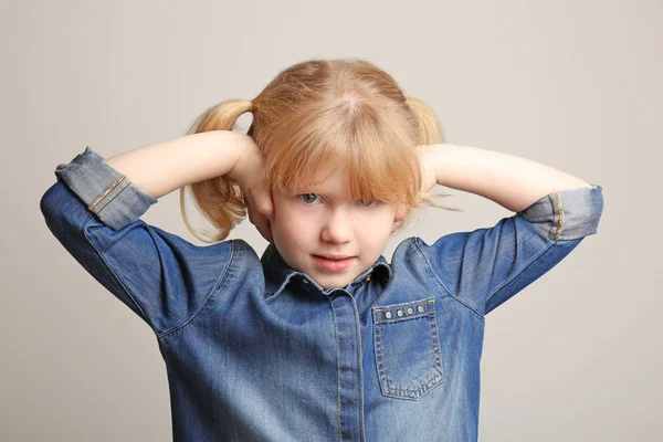 Nettes kleines Mädchen mit Hörproblemen auf grauem Hintergrund — Stockfoto