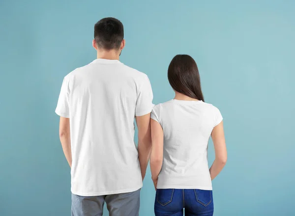 Ung man och kvinna i eleganta vita t-shirts på färgbakgrund. Mockup för design — Stockfoto