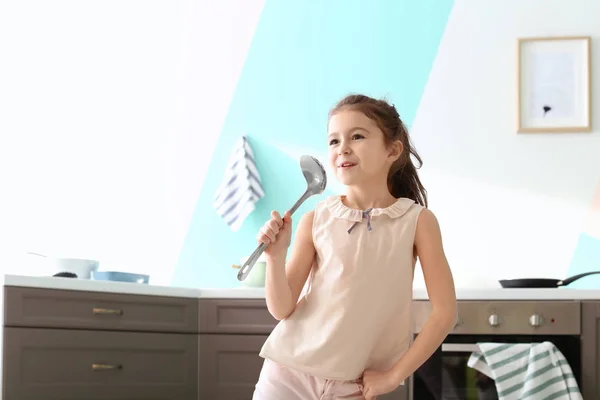 Petite fille mignonne signer chanson en louche cuillère dans la cuisine — Photo