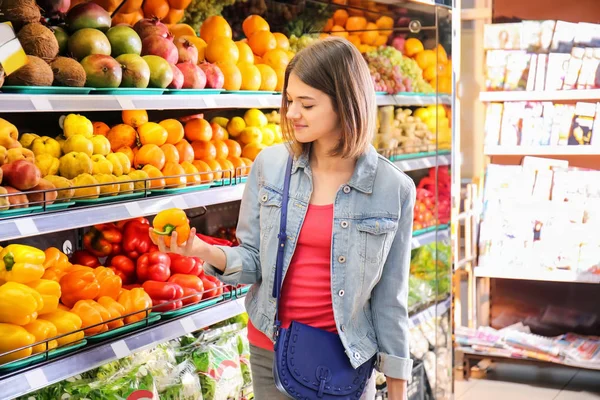 Beautiful woman with product list choosing fresh bakery in supermarket