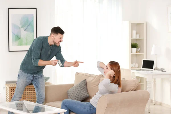 Hombre enojado regañando a su esposa por gastar en exceso en casa — Foto de Stock