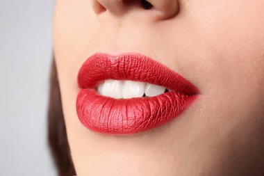 Gri arka plan, closeup parlak dudak makyaj ile genç kadın
