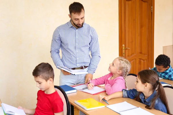 Professora do sexo masculino ajudando menina com seu dever de casa em sala de aula na escola — Fotografia de Stock