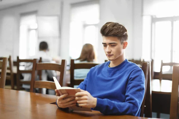 Студент с книгой в библиотеке — стоковое фото