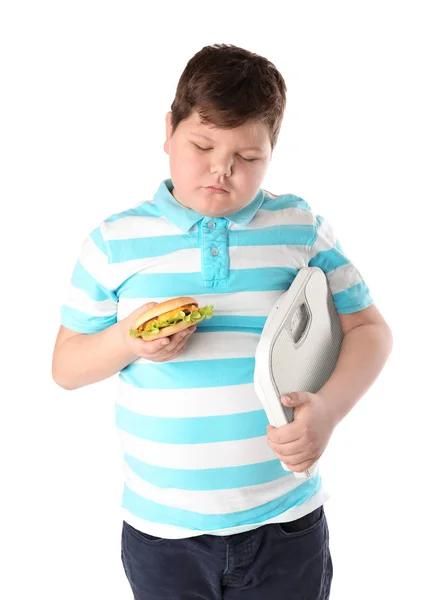 Menino com excesso de peso com escalas de chão e hambúrguer sobre fundo branco — Fotografia de Stock