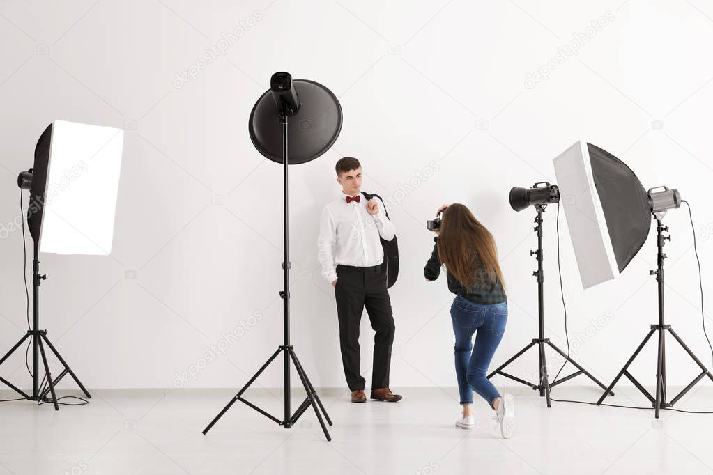 Young man posing for professional photographer on white background in studio