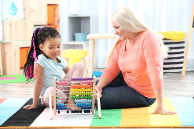 Kadın Olgun dadı kullanarak Abacus saymak için küçük Afrikalı-Amerikalı kız öğretim