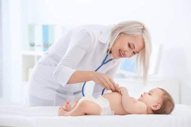 Female doctor examining baby boy in clinic clipart