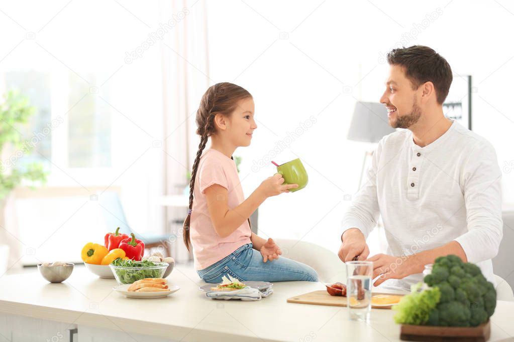 Father and daughter preparing breakfast together in kitchen