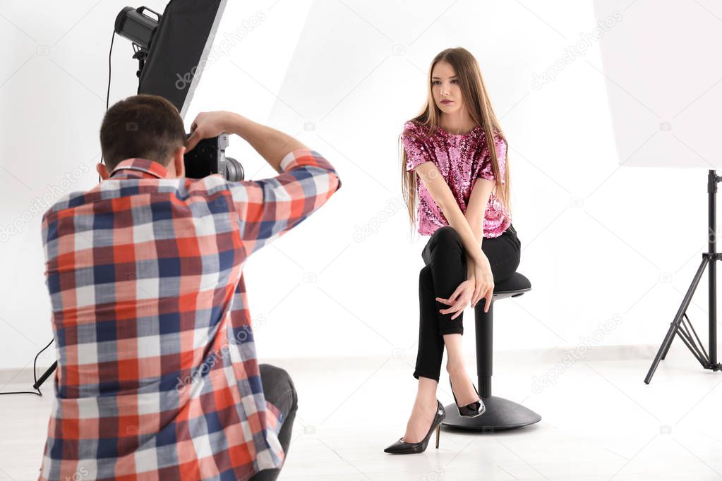 Young woman posing for professional photographer on white background in studio