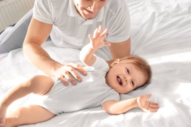 Küçük oğluyla evde yatakta oynayan genç baba