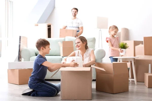 Young couple packing boxes with their children indoors. Happy family on moving day