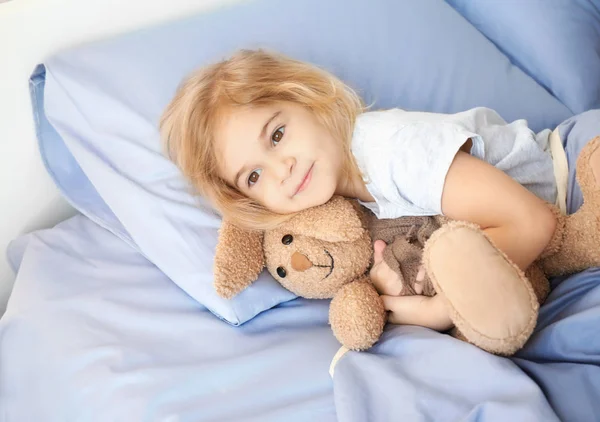 可爱的小女孩与兔子玩具躺在床上在家 — 图库照片
