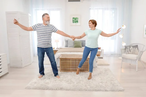 Happy mature couple dancing at home