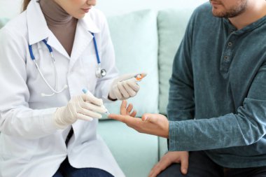Doktor diyabetik hastanın kan şekeri düzeyini kontrol etmek için mazgal kalem ve dijital şeker ölçüm kullanarak