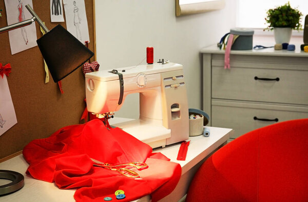 Sewing machine with fabric on table in tailor workshop