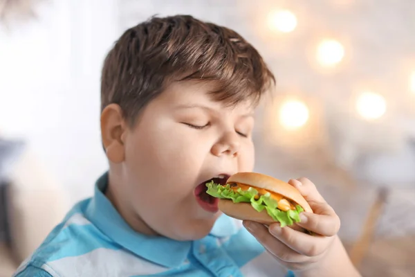 Overweight Boy Eating Burger Indoors — Stock Photo, Image