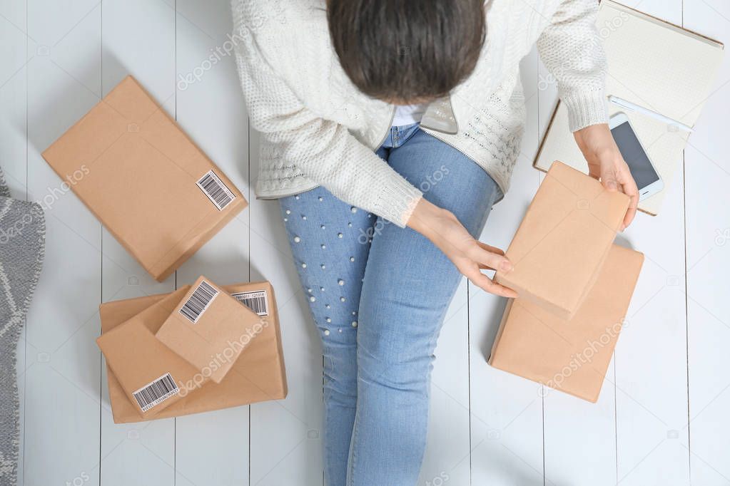 Female startupper preparing parcels for shipment to customers indoors