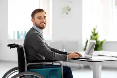 Young man in wheelchair at workplace clipart