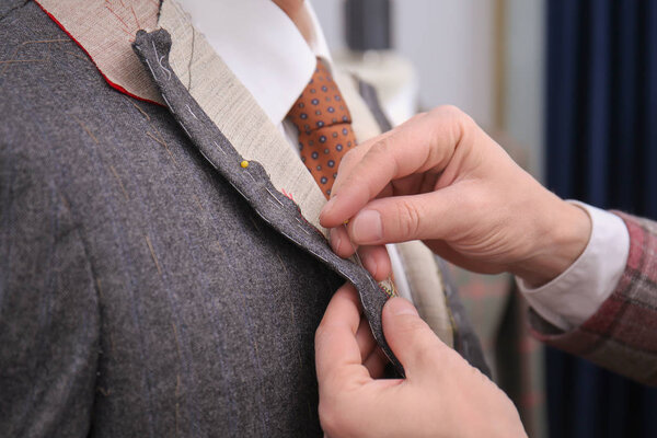 Tailor with client in atelier. Choosing fabric for custom made suit