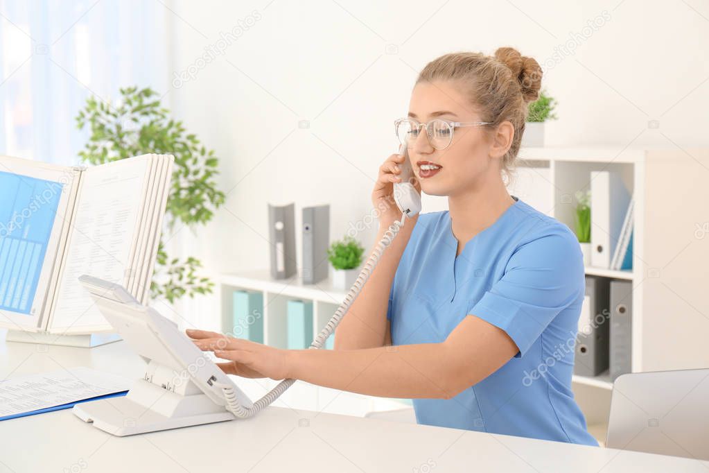 Telephone and receptionist with trainee in hospital